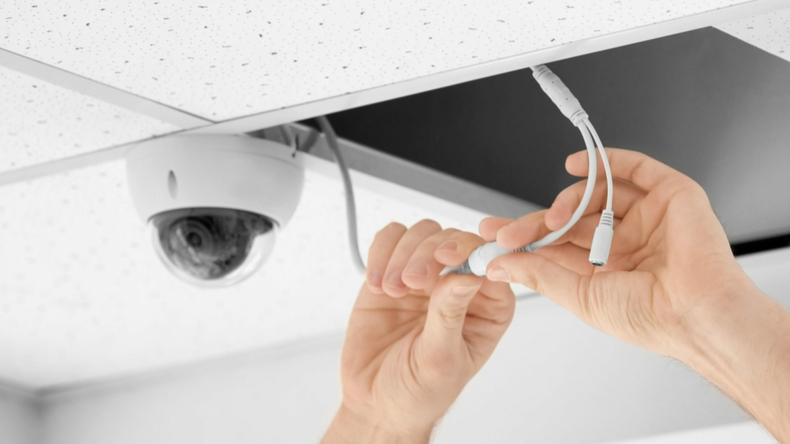 Technician installing CCTV camera on ceiling indoors