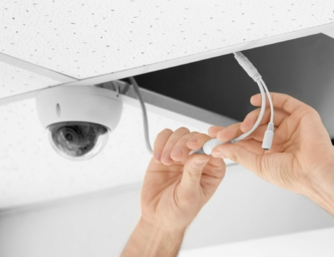 Technician installing CCTV camera on ceiling indoors